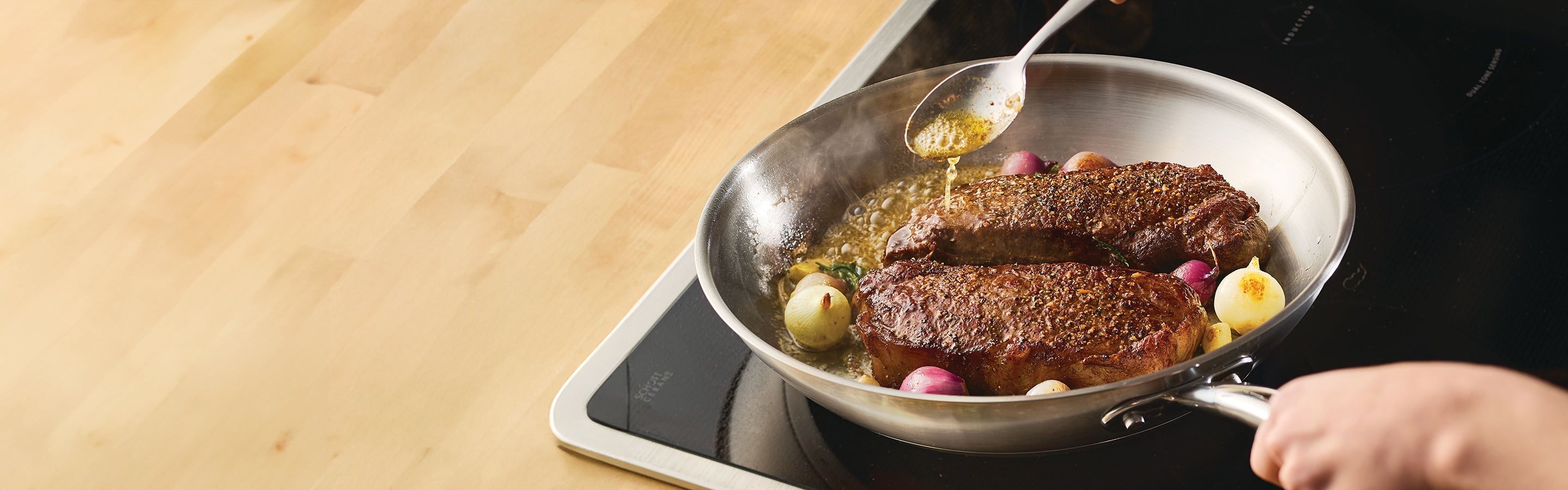 Assorted pots, pans, and fresh vegetables, including tomatoes and Brussels sprouts, are arranged on a kitchen countertop with a white tile backsplash.