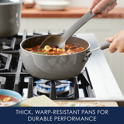 Stirring a pot of soup on a stove with a gray spoon and pot.