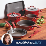 Red cookware set on wooden surface with vegetables nearby.