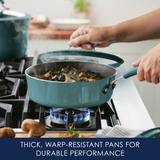 Hands lifting a lid from a steaming teal pan on a gas stove.