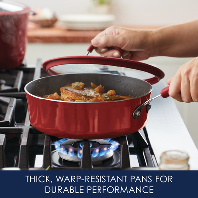 Person cooking with a red pan on a stove.