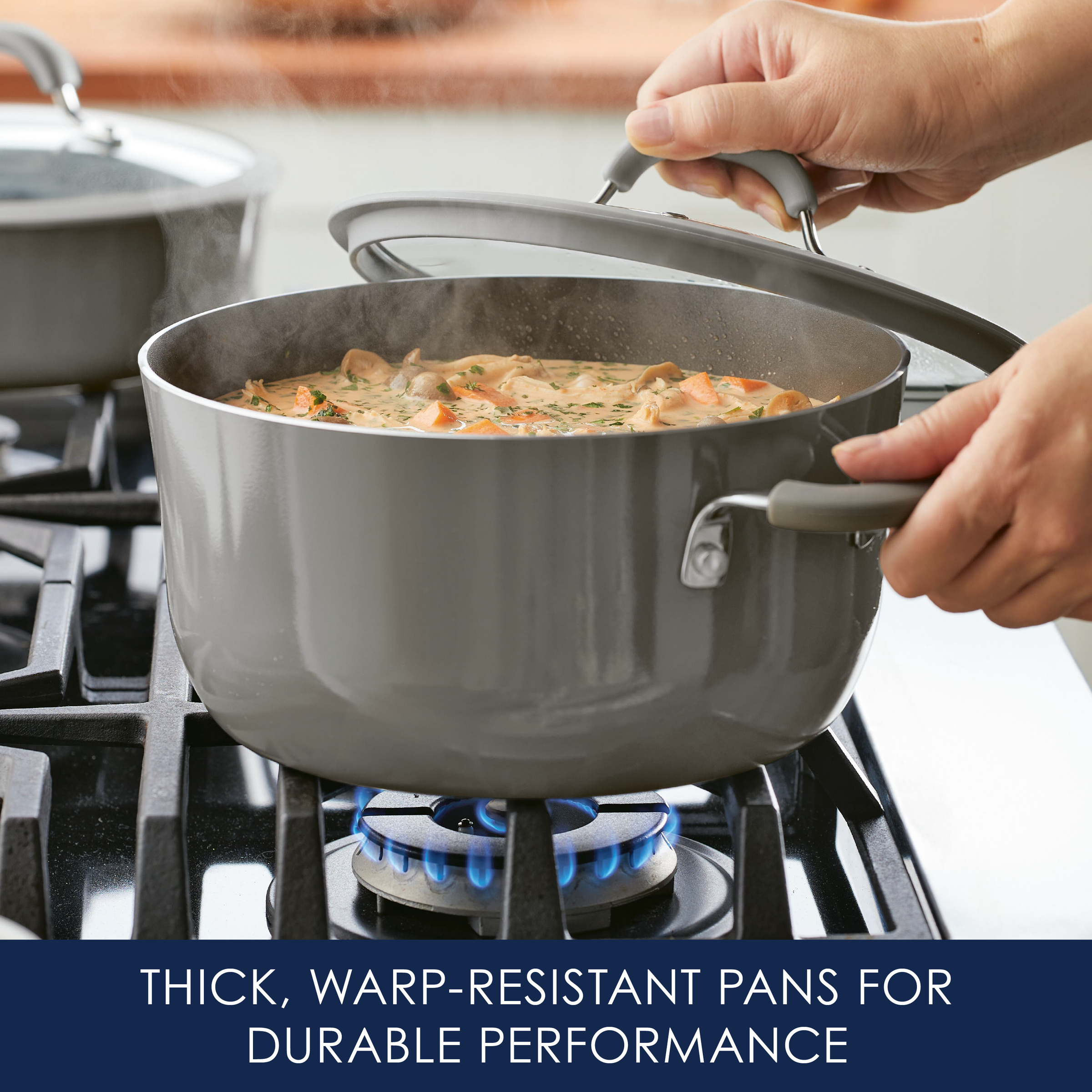 A person places the lid on a 5-Quart Cook + Create Nonstick Dutch Oven, which is gray and simmering stew on a gas stove, ideal for stove-to-oven recipes.