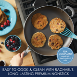 Pancakes cooking in a nonstick pan on a stove next to a plate of berries.