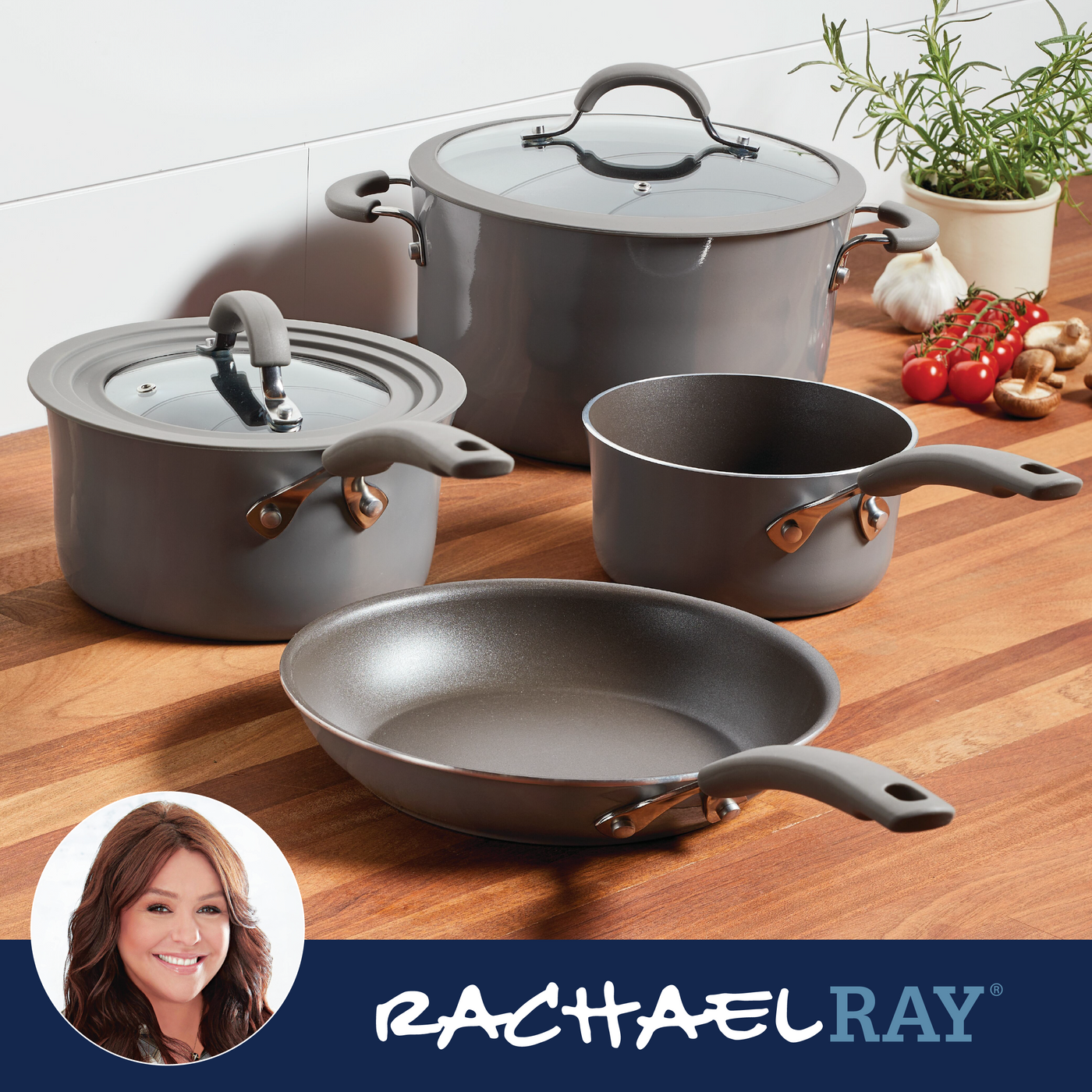 Gray cookware set on a wooden surface with herbs and vegetables nearby.