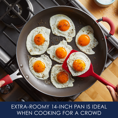 A large pan on a stove cooking multiple sunny-side-up eggs.