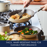 Two pans on a stove cooking chicken with lemon and vegetables.