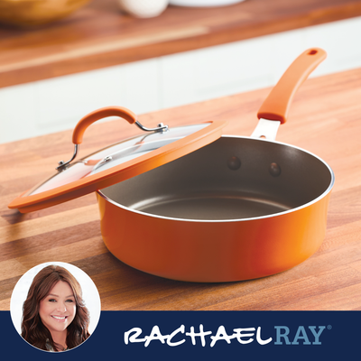 Orange saucepan with a glass lid on a wooden counter, labeled Rachael Ray.