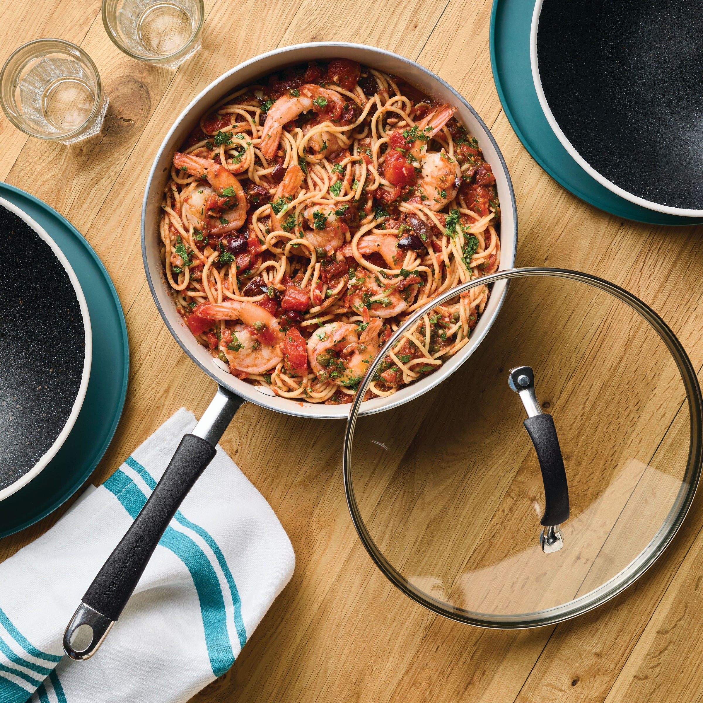 Shrimp pasta in a pan with a glass lid on a wooden table.
