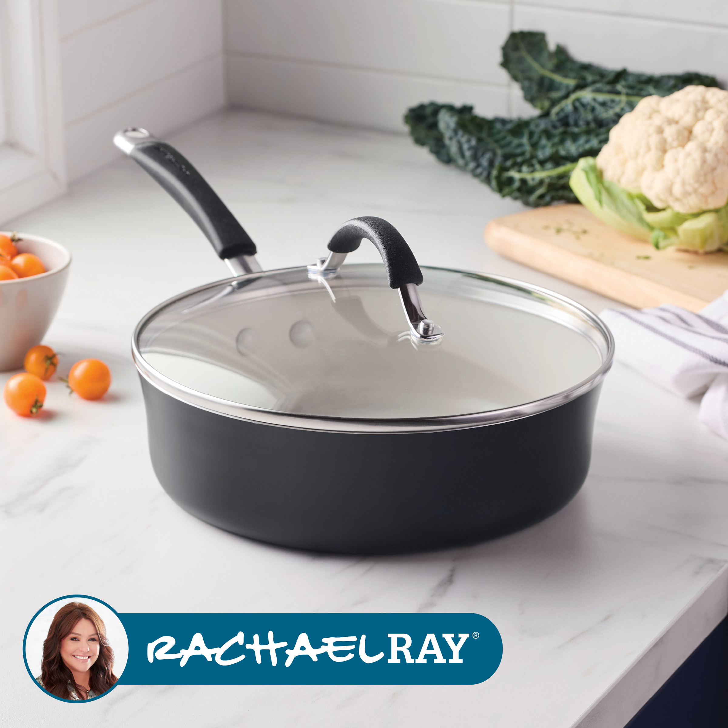 Black saucepan with glass lid on kitchen counter near vegetables.