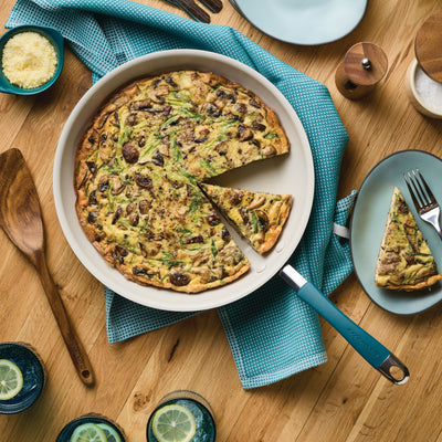 Vegetable frittata in a pan with a slice served on a plate.