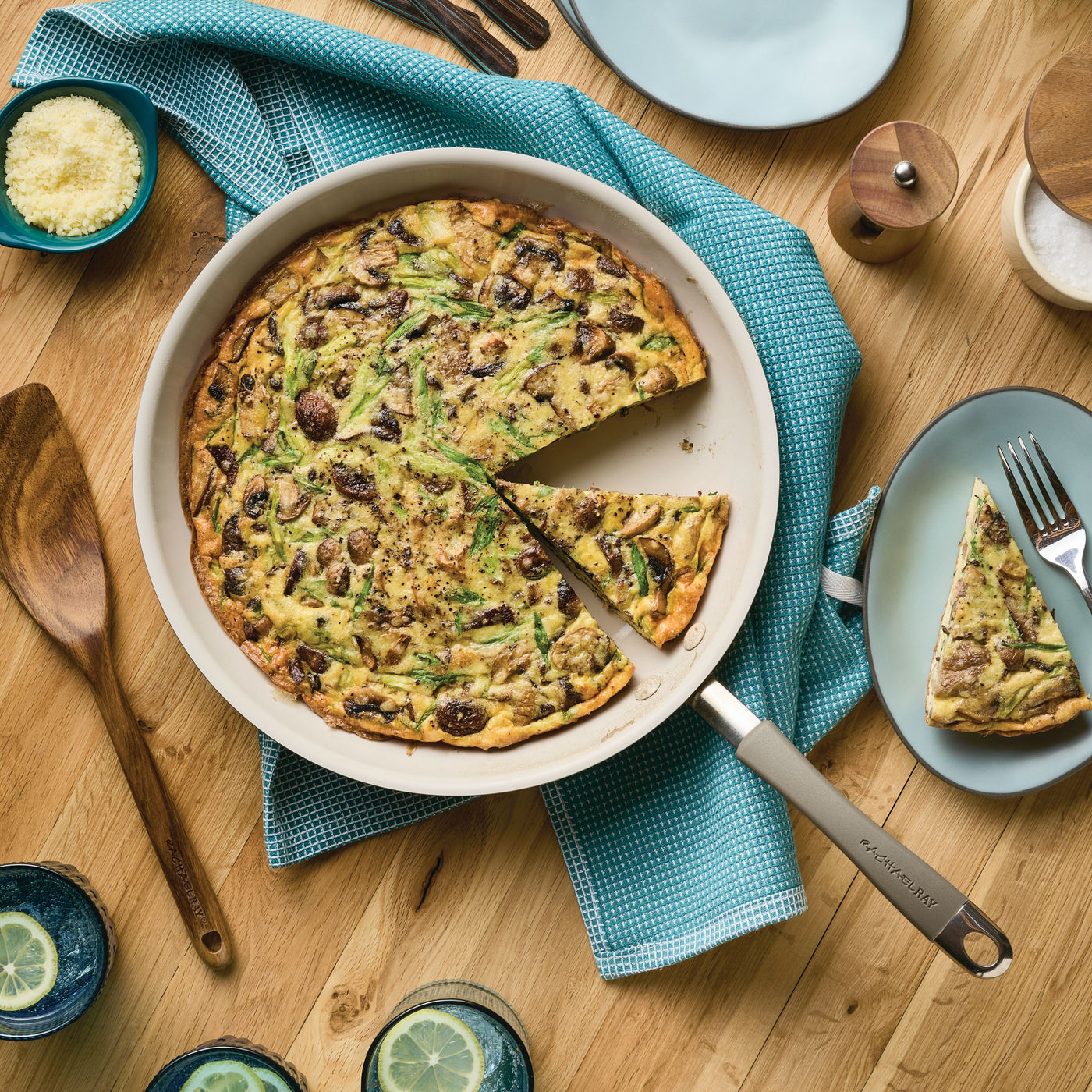 Frittata in a skillet with one slice served on a plate, on a wooden table.