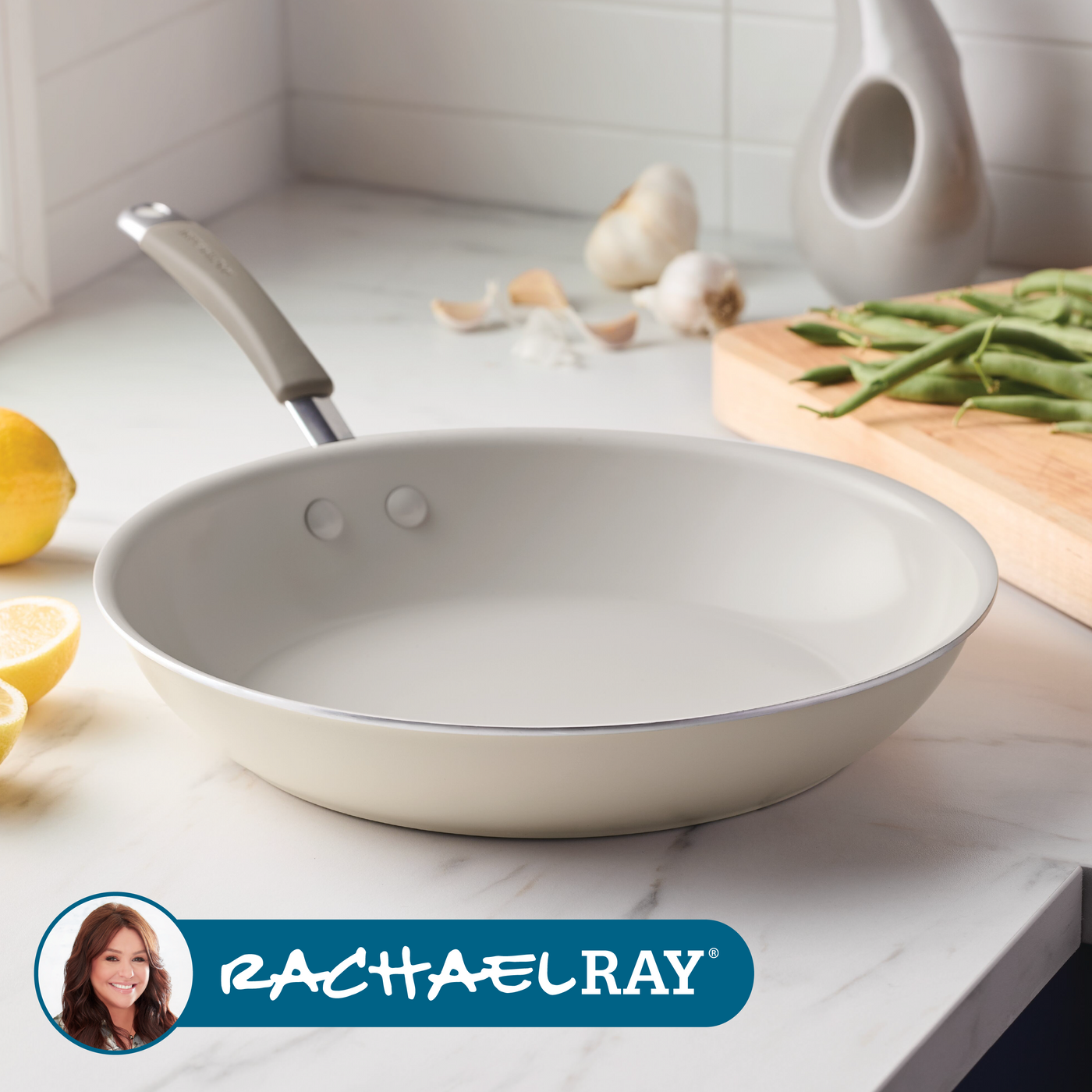 A white frying pan on a kitchen counter with green beans and lemons nearby.