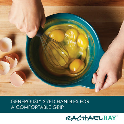 Hands whisking eggs in a blue bowl on a wooden surface.