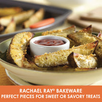 Potato wedges with dip on a plate next to a Rachael Ray 3-Piece Nonstick Sheet Pan Set, crafted from durable steel and conveniently oven safe.