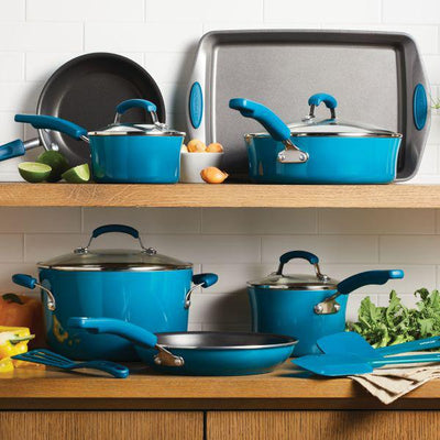 Blue cookware set on wooden shelves with kitchen utensils and vegetables.