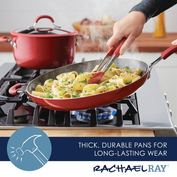 A high-performance red Cook + Create Nonstick Frying Pan on the stove holds pasta, with a red pot in the background. This frying pan ensures easy cooking and cleanup, making it a kitchen favorite.