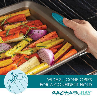 Hand placing a tray of colorful vegetables in the oven with silicone grips.