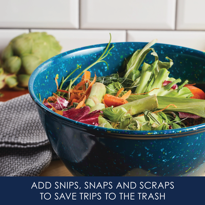 Blue bowl with vegetable scraps on a kitchen counter.