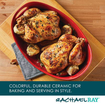 Two roasted chickens in a red ceramic baking dish with garlic.