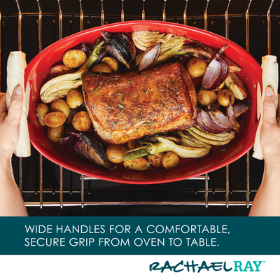 Person holding red baking dish with roast and vegetables in an oven.