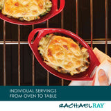 Two oval red dishes with baked cheesy dish on oven rack.