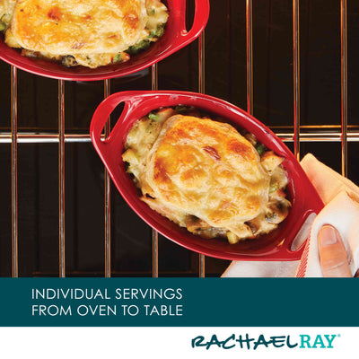 Two oval red dishes with baked cheesy dish on oven rack.