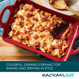 Baked pasta in a red ceramic dish with a wooden spoon on the side.