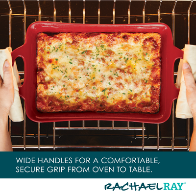 Hands holding a red baking dish with lasagna in an oven.