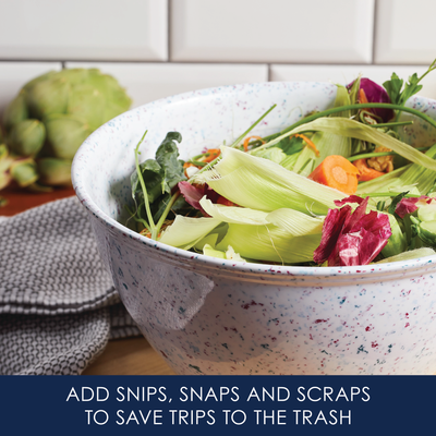 Bowl of vegetable scraps on a kitchen counter with a towel nearby.