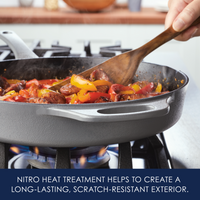 A cast iron skillet on a stove, cooking vegetables and sausages.