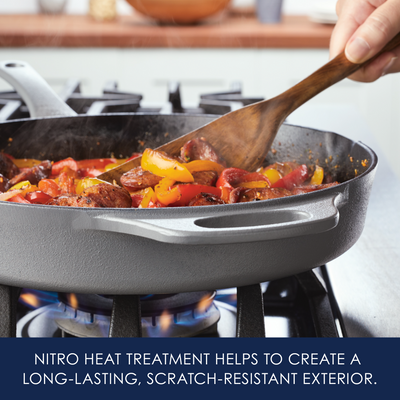 A cast iron skillet on a stove, cooking vegetables and sausages.