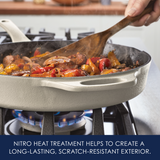 Cooking vegetables and meat in a cast iron skillet on a stove.