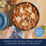 Person stirring pasta in a skillet with melted cheese on top.