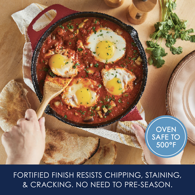 Skillet with eggs in tomato sauce, bread on the side, and cilantro garnish.