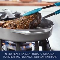 A steak being cooked in a skillet with blue tongs holding the meat.