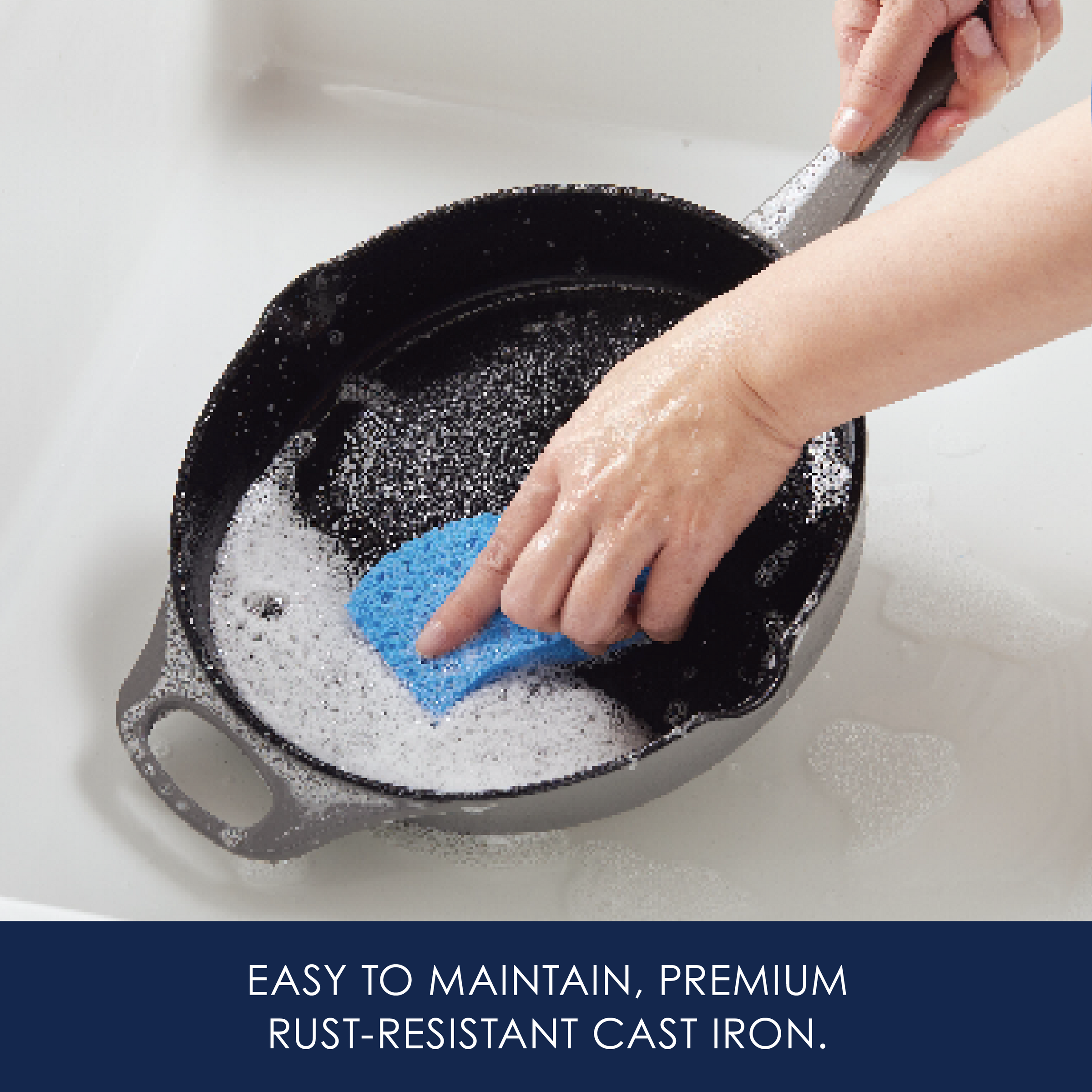 Person cleaning a cast iron skillet with a sponge in soapy water.