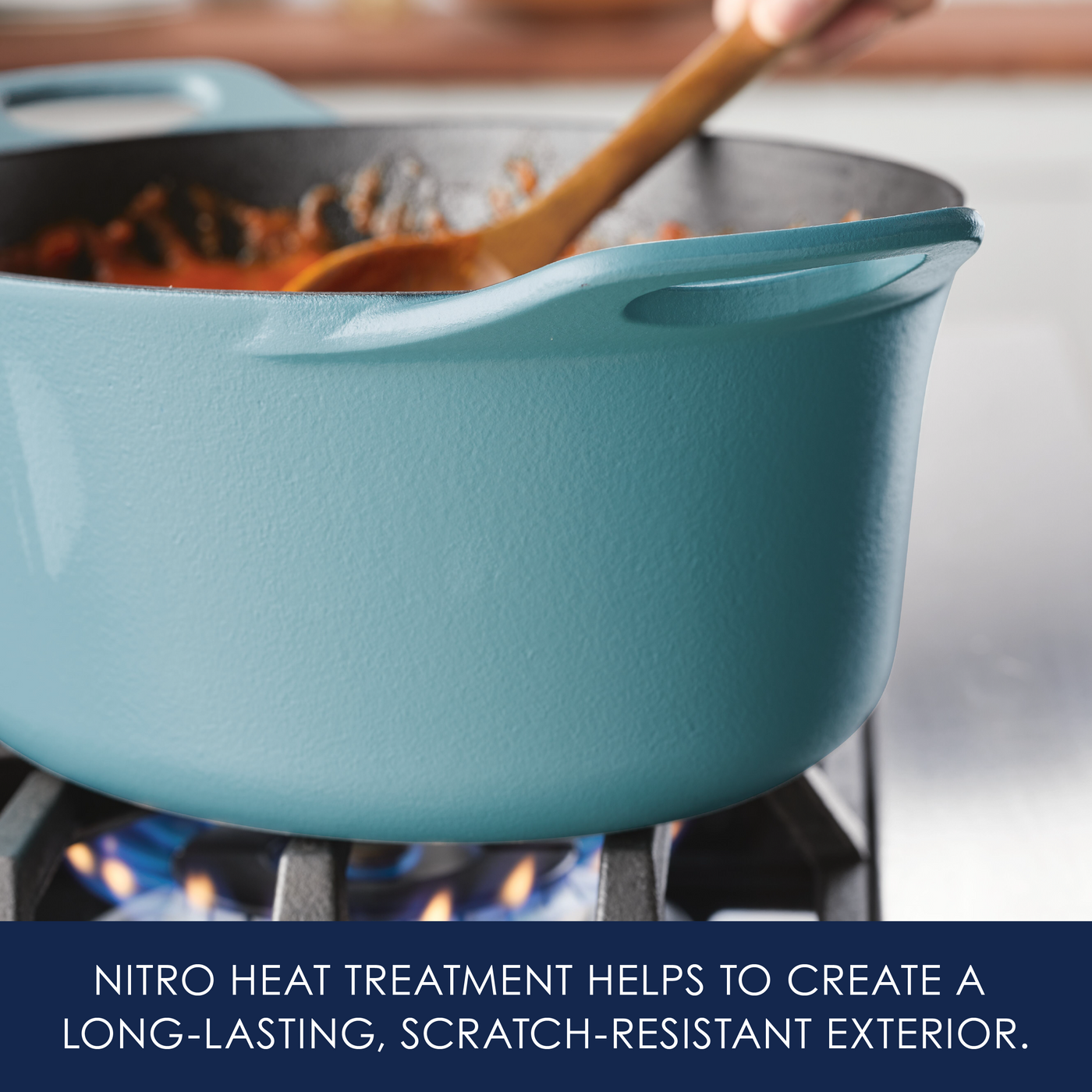A blue pot on a stove with a wooden spoon stirring food inside.
