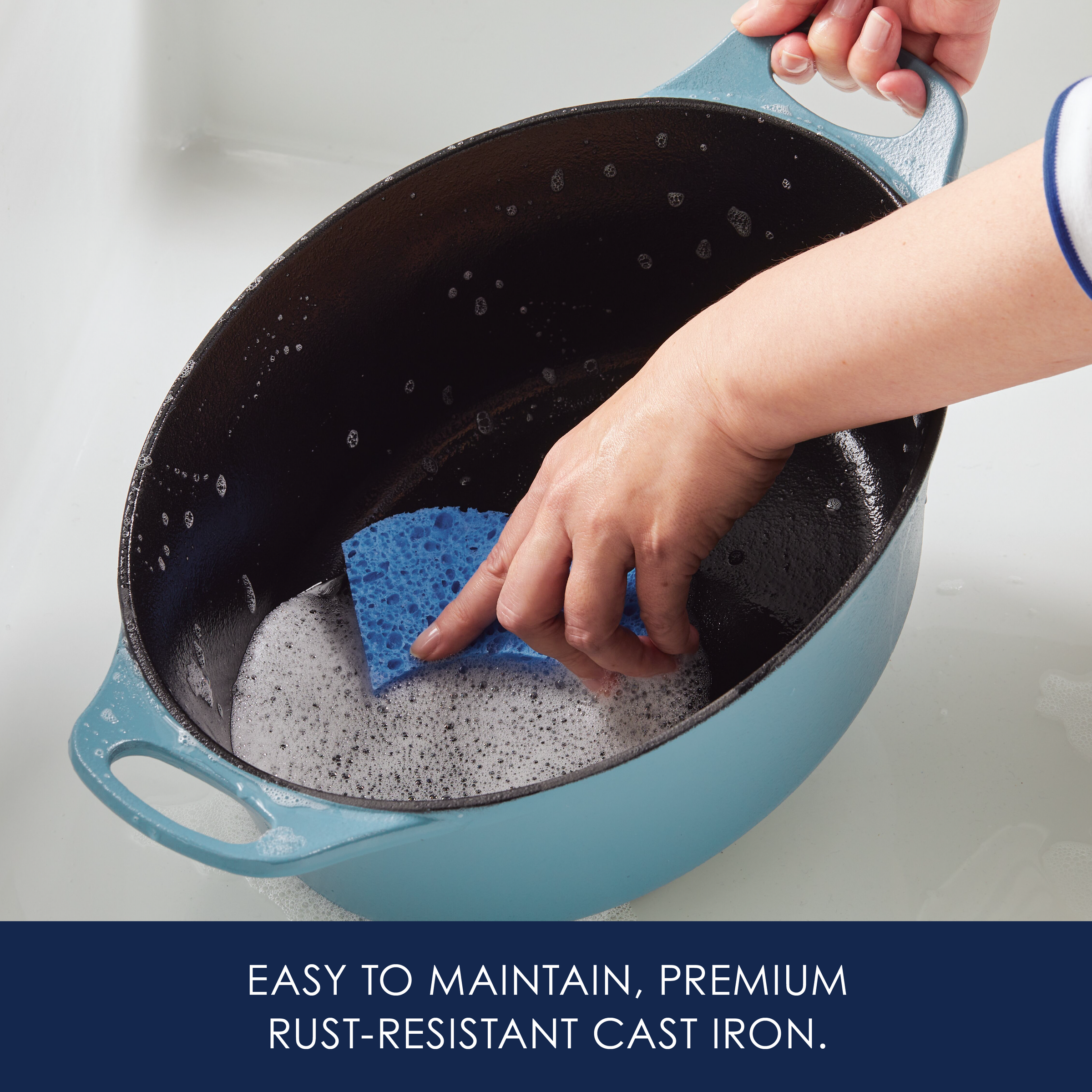 Person cleaning a blue cast iron pot with a sponge.
