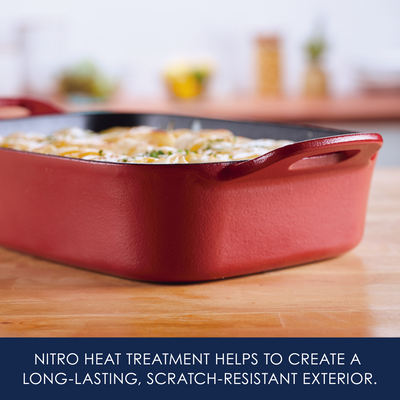 Red baking dish with food on a wooden surface.