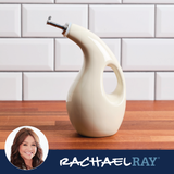 A white oil dispenser on a wooden countertop, with a brick wall background.