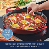 Red cast iron pan with eggs and tomato sauce on a stovetop.