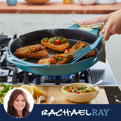 Cooking breaded fish with vegetables in a skillet on a stove.