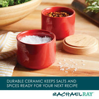 The Stacking Spice Box Set, crafted in red ceramic and filled with salt and spices, adorns a wooden kitchen counter.