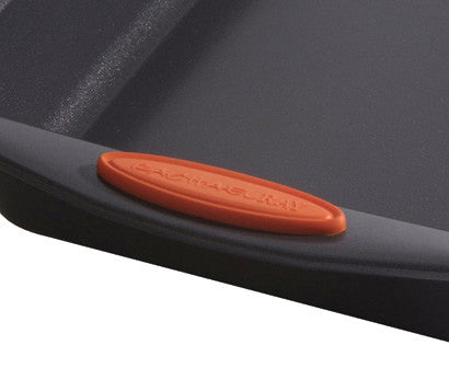 Close-up of a black baking sheet with an orange handle grip.