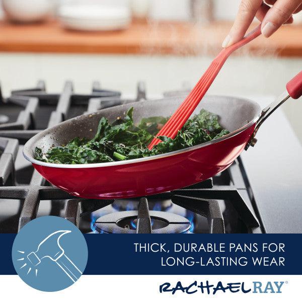 A red pan from the Cook + Create Nonstick Cookware Sets on a gas stove exemplifies nonstick cookware at its best, with greens being expertly sautéed using a red utensil.