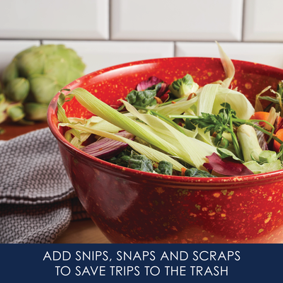 Red bowl filled with vegetable scraps on a kitchen counter.