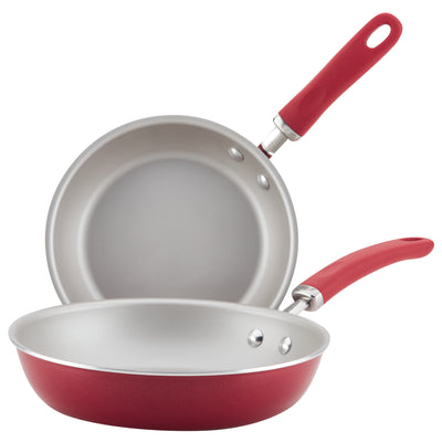 Two red frying pans with handles, one stacked inside the other.