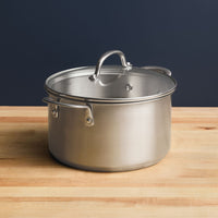 A 6-Quart Stainless Steel Induction Stockpot with Lid sits elegantly on a wooden surface, embodying professional-grade standards.