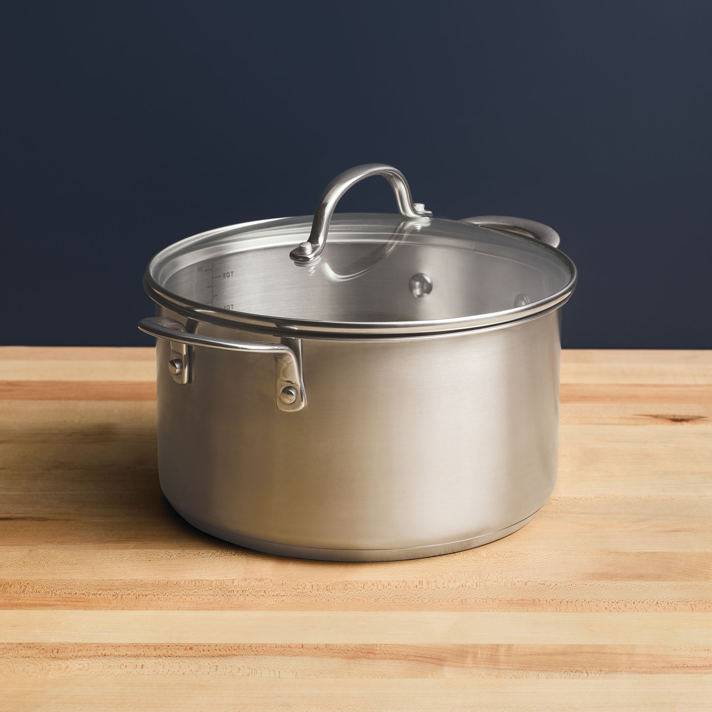 A 6-Quart Stainless Steel Induction Stockpot with Lid sits elegantly on a wooden surface, embodying professional-grade standards.