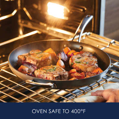 Pork chops and vegetables in a skillet inside an oven set to 400°F.